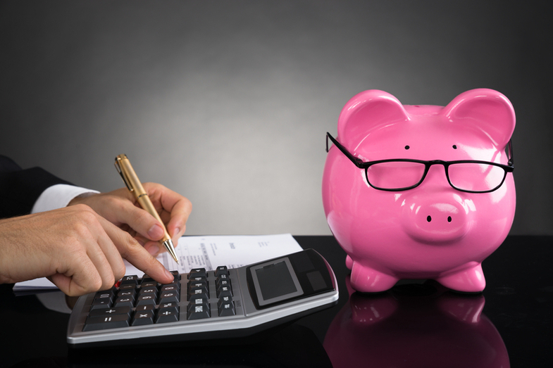 Hands with pen and calculator. Pink Piggy Bank with comedy glasses